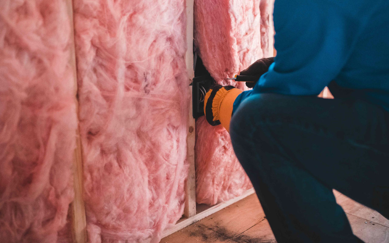 Glaswolisolatie wordt aangebracht in de muur