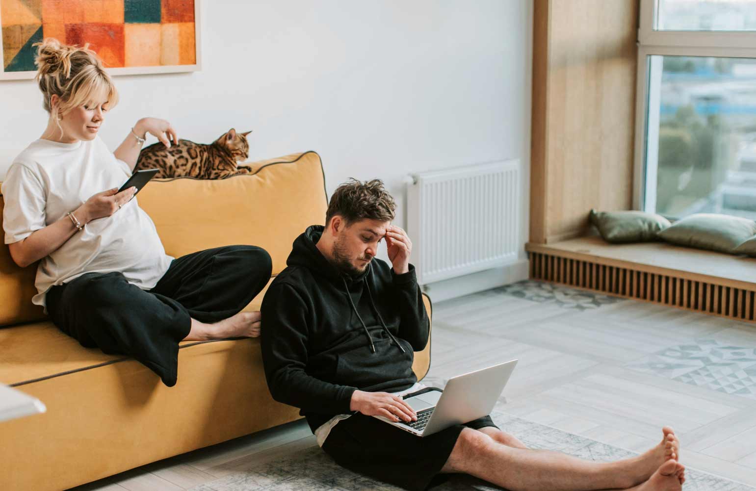 Man en vrouw in de woonkamer. man zit op de verwarmde vloer te werken